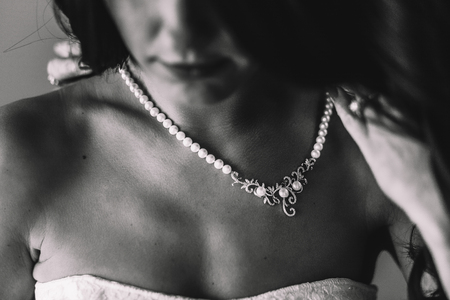 Blurred picture of beautifyl pearl necklace lying on tender woman's chestの写真素材