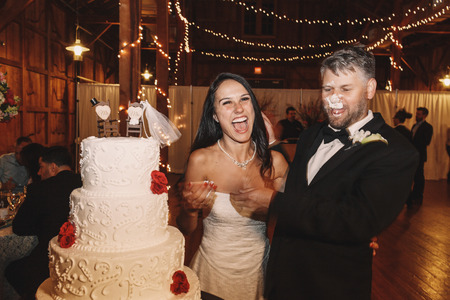 Groom with face in wedding cake stands behind a brideのeditorial素材