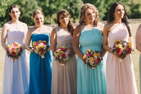 Smiling bridesmaids in pastel dress stand in a row behind the brideの写真素材