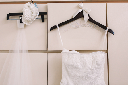 Garter, veil and dress hang on the white wardrobeの写真素材