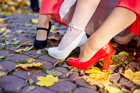 Bride's leg in white shoe and bridesmaids' feet in red and black oneの写真素材