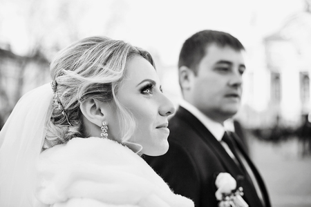 Black and white picture of magnificent bride looking up in the air while standing with a groomの写真素材