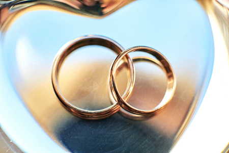 Closeup of wedding rings lying on the golden plateの写真素材