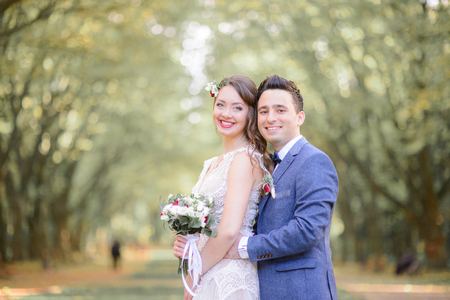 Fabulous wedding couple stands in green and yellow autumn parkの写真素材