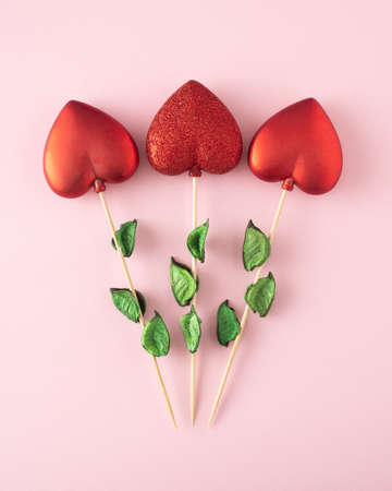Three red hearts on a twig like flowers. Concept of Valentines day on pink background.の写真素材
