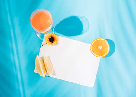 Summer organic fruit composition on cyan blackground. Flat lay concept with fruit,copy paste space,  palm shade and glass of juice.の写真素材