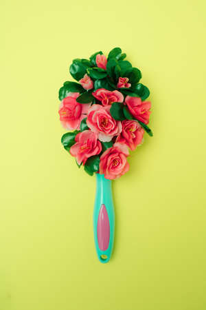 Hair brush made of flowers. Minimalist floral concept on a yellow background.の写真素材