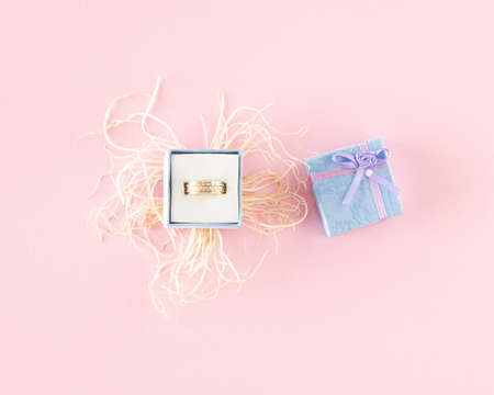 Ring in a box from which roots have sprouted . Minimal concept on light pink background.