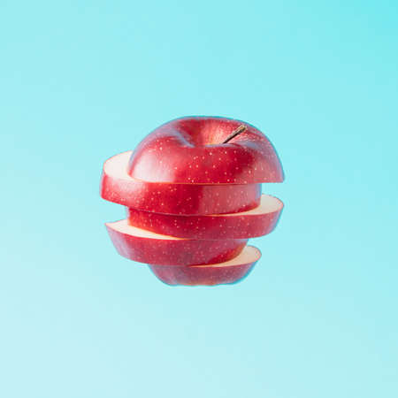Red apple cut into pieces that are arranged vertically.Summer minimal concept on a light blue background.の写真素材