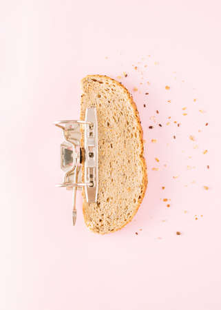 A slice of bread placed in the folder as paper. Minimal school concept on pink background