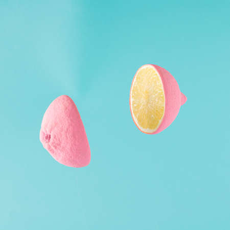 A pink lemon cut in half and its slices flying in the air. Minimal fruit conceptの写真素材