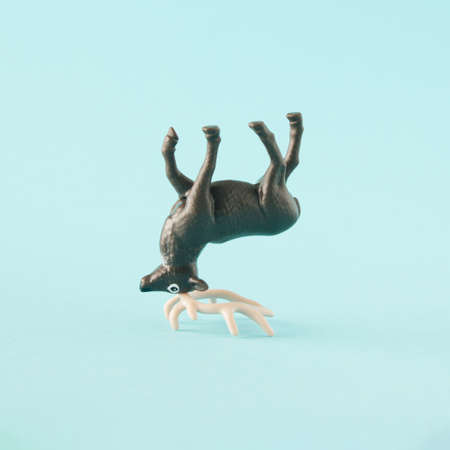 Brown deer turned upside down and standing on its horns. Minimal funny New Year's concept on a light...