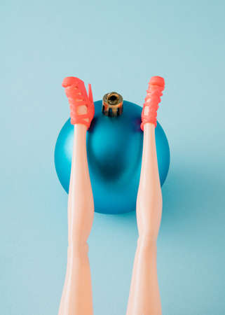 Female legs in red sandals in a supine position leaning on a Christmas blue ball. Minimal New Year's relexation conceptの写真素材