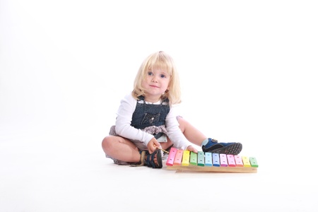 Studio shot of a cute little blonde girl playing a rainbow-colored musical toy.の写真素材