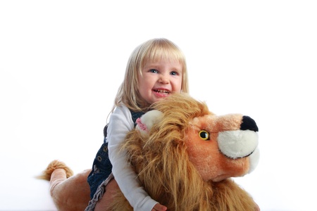 Studio shot of a happy blonde little girl riding her toy lionの写真素材