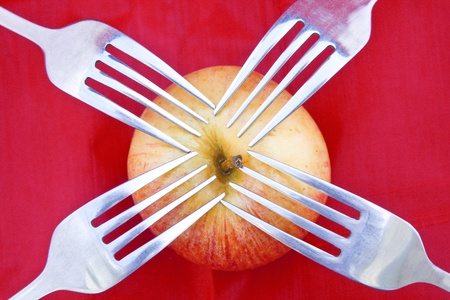 Golden red apple and four forks as for sharing a common source or healthy lifestyle.の写真素材