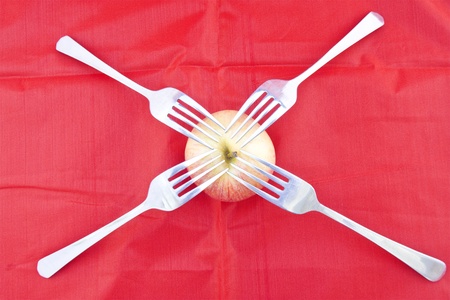 Golden-red apple on red with four forks as for sharing healthy lifestyle.の写真素材