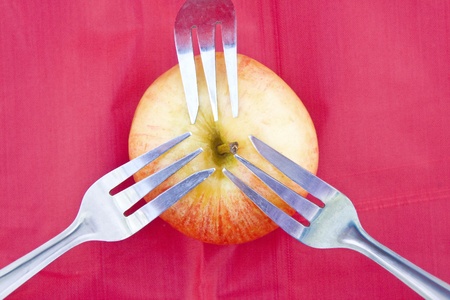 Close up on golden-red apple with three dessert forks as for sharing a common source or metaphor of healthy lifestyle.の写真素材