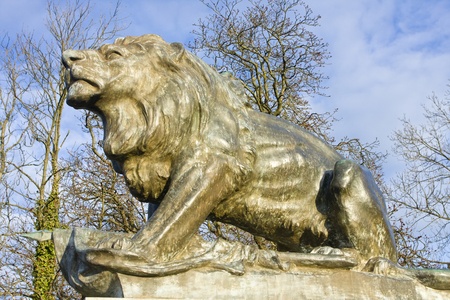 Granite gate lion against early spring countryside.