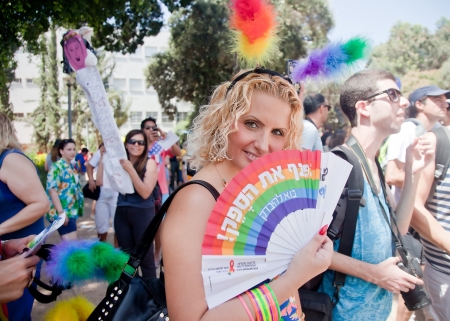 TEL AVIV - JUNE 06: Young beautiful female supporter of Pride Parade poses at the camera with rainbow fan with gay pride slogan in Hebrew in Tel Aviv, Israel on June 06, 2013のeditorial素材