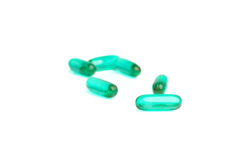 Green pills on white background with reflections