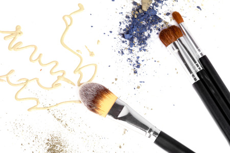 Makeup tone and eyeshadow colors on white surface with professional brushesの写真素材