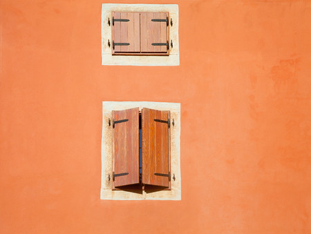 Old wall detail with two medieval style blinded windowsの写真素材