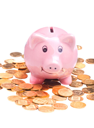 Pig-shaped pink money box and golden coins isolated over white backgroundの写真素材