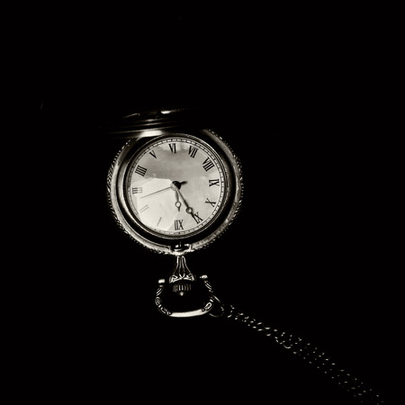 Old retro watch over black showing five to midnight (monochrome toning)の写真素材