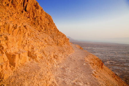 Dangerous path on the mountain slope in Negev desert at sunsetの写真素材