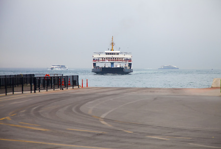 Ferry boat approaching the moor in Istanbul on a cloudy morningの写真素材