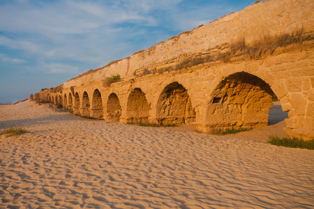 Ancient Roman aqueduct in Caesarea, Israel at sunset (sunset lighting)の写真素材