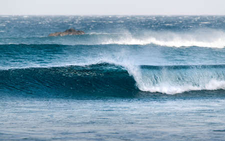 Small set of waves breaking on the beach forming a tube. Beautiful blue ocean waterの写真素材