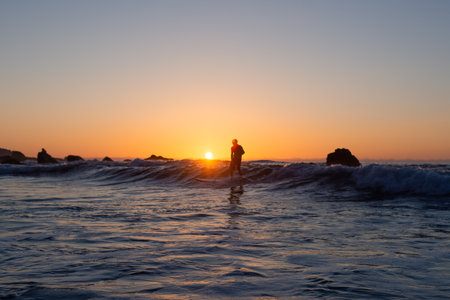 Silhouette of a man surfing at sunset