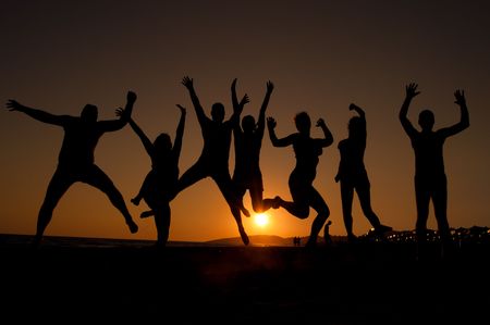 group of happy young people silhouettes jumping on the beach   on beautiful summer sunset の写真素材