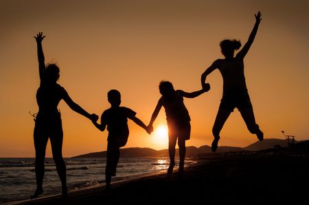Silhouette of family jumping on the beach   on beautiful summer sunset の写真素材