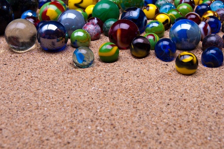 Colored glass marbles on a sandy backgroundの写真素材