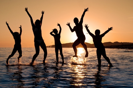Silhouette of family jumping on the beach on beautiful summer sunsetの写真素材