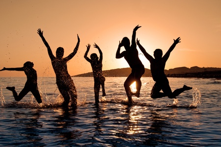 Silhouette of family jumping on the beach on beautiful summer sunsetの写真素材