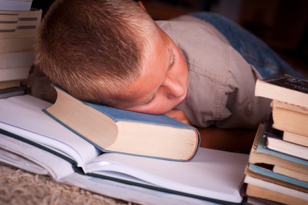 Image of young boy sleeping near booksの写真素材