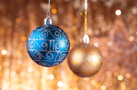 Blue and gold christmas baubles on background of defocused golden lights.の写真素材