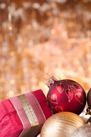 gold and red christmas baubles and red box on background of defocused golden lights.の写真素材
