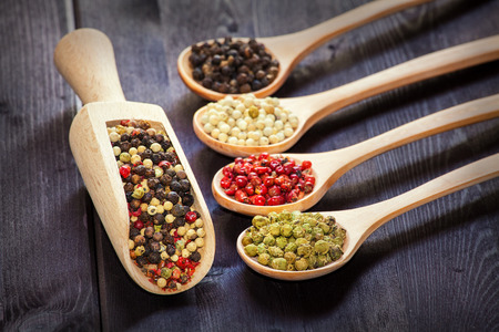 Mixed green, red, white and black peppercorns in a wooden spoon, shallow depth of fieldの写真素材