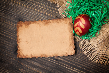 Red Easter egg and old vintage paper card on wooden backgroundの写真素材