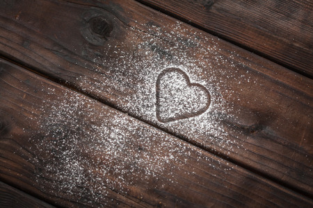 shape of a heart with powdered sugar on wooden backgroundの写真素材