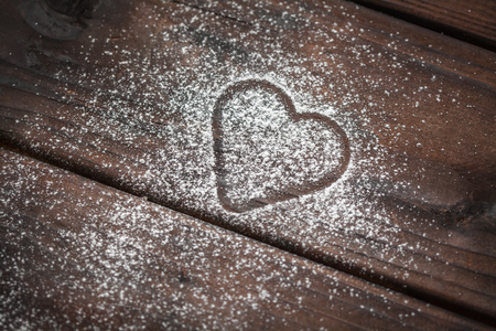 shape of a heart with powdered sugar on wooden backgroundの写真素材