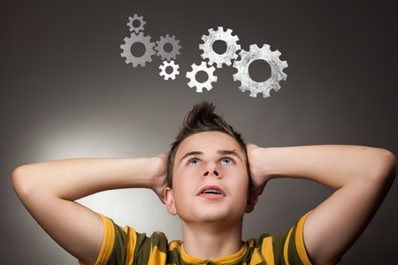 Young boy looking up at gear wheel - student wfith brainstormingの写真素材