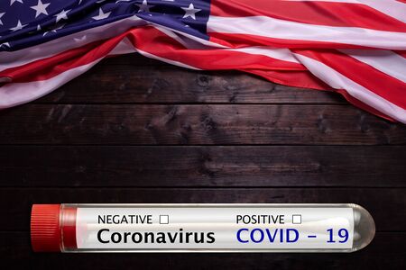 Closeup of grunge flapping flag USA with wave and Coronavirus blood test tubeの写真素材