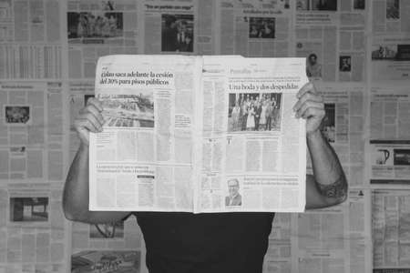 Barcelona, Spain, April 5, 2020: Man reading news in front of a newspaper wall. Over informed....
