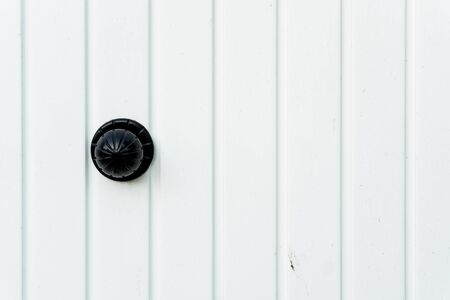 White classic wooden door with a classic black door knob. Horizontal capture with vertical stripes.の写真素材